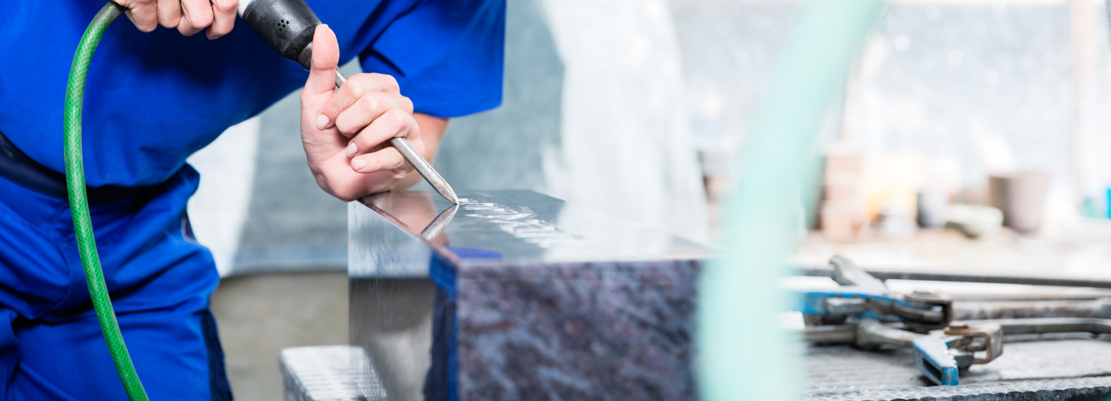 A stone mason using a power tool on a piece of marble.