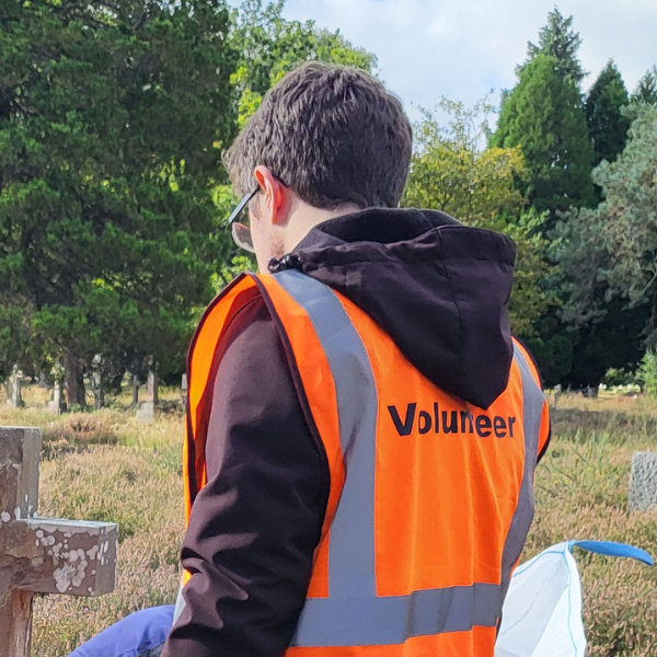Male wearing an orange high visibility vest that says volunteer on the back.