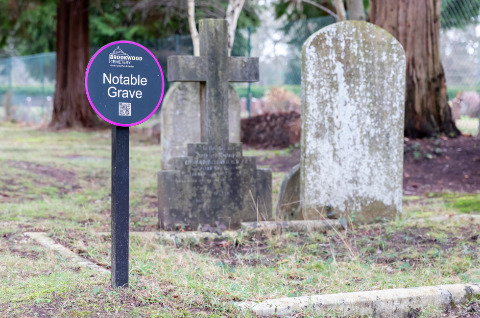 A marker next to a notable grave within the cemetery. It has QR code to find out more about the person buried in the grave.