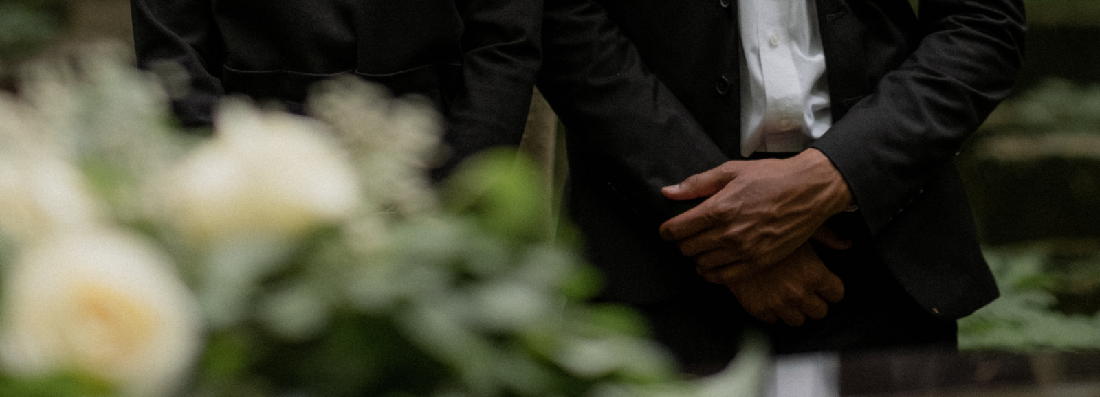 Close up of white roses and in the background a pair of male hands