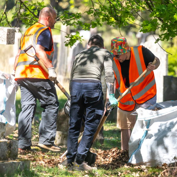 A group of three male colleagues working together to clear leaves.