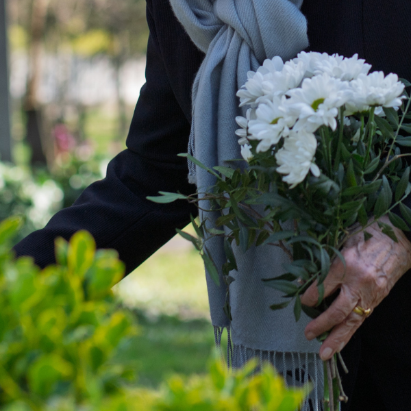 Female putting fresh cut flowers on a grave