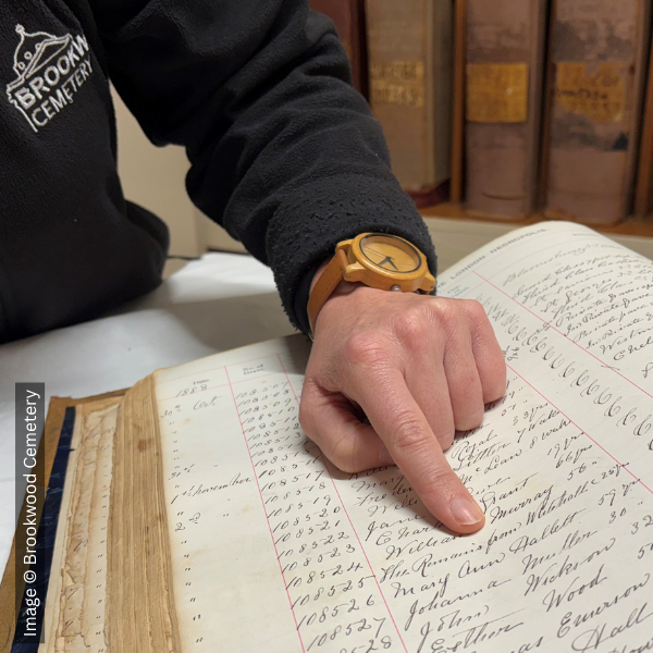 Finger pointing to an entry in the burial register which says 'the remains from Whitechapel'